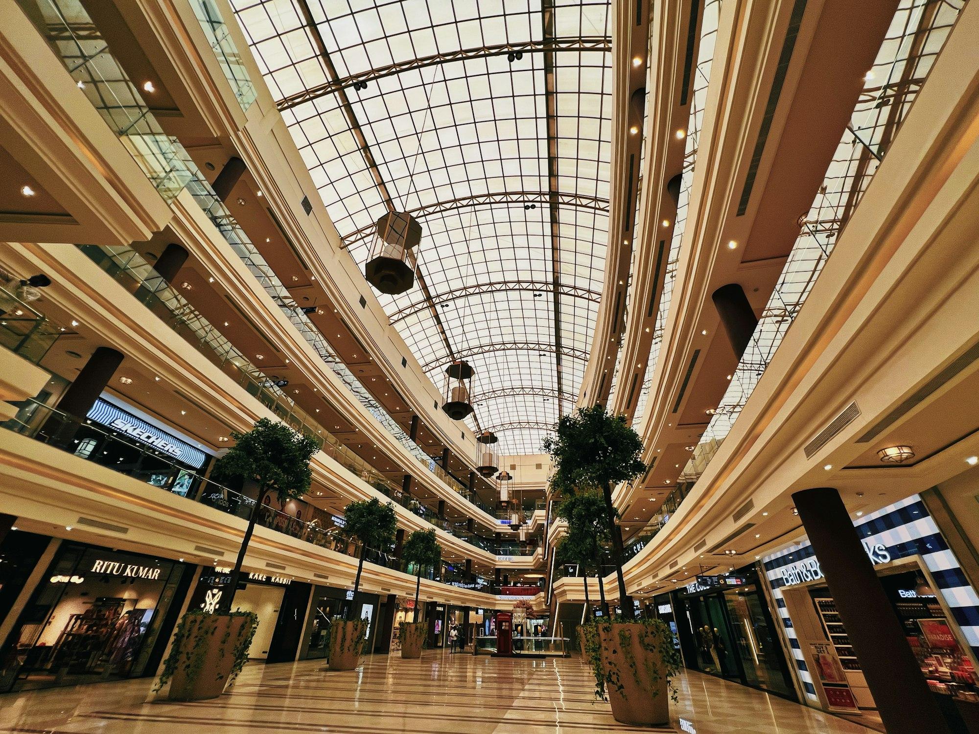 The bright multi-level atrium of a modern shopping mall under a glass roof