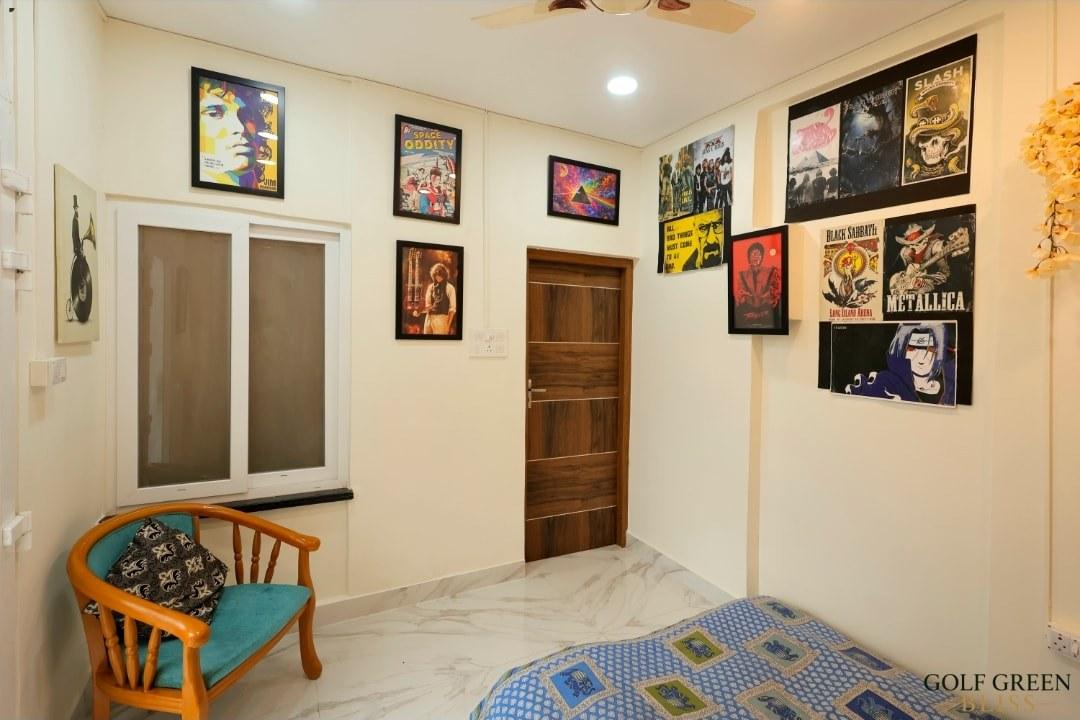 Bedroom three, its walls covered in framed music and film posters, with a floor mattress and a teak armchair