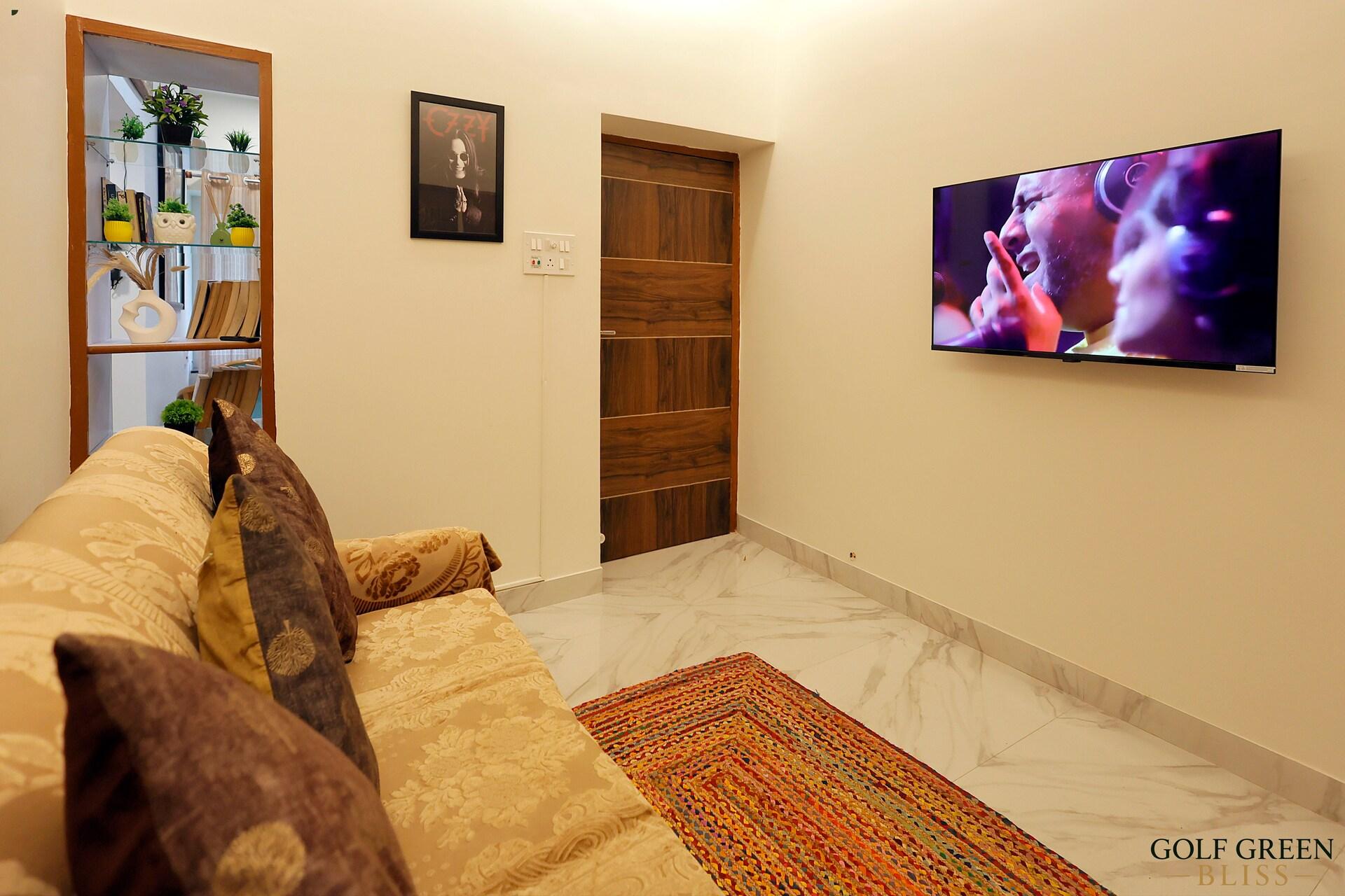 The living room sofa and wall-mounted television seen from the doorway